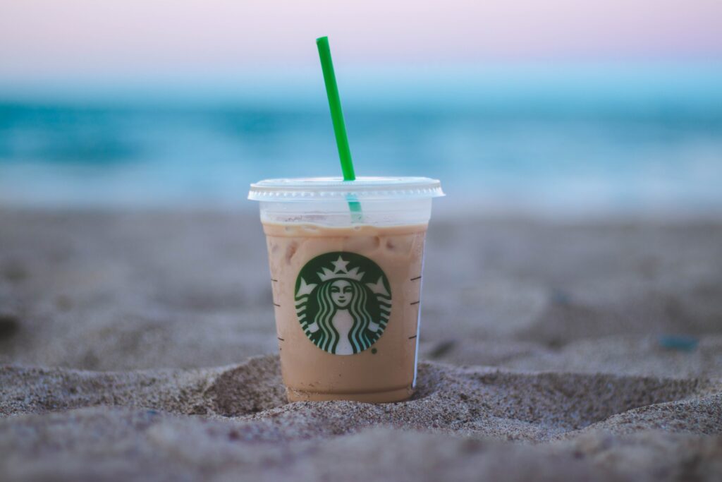a cup of starbucks sitting in the sand